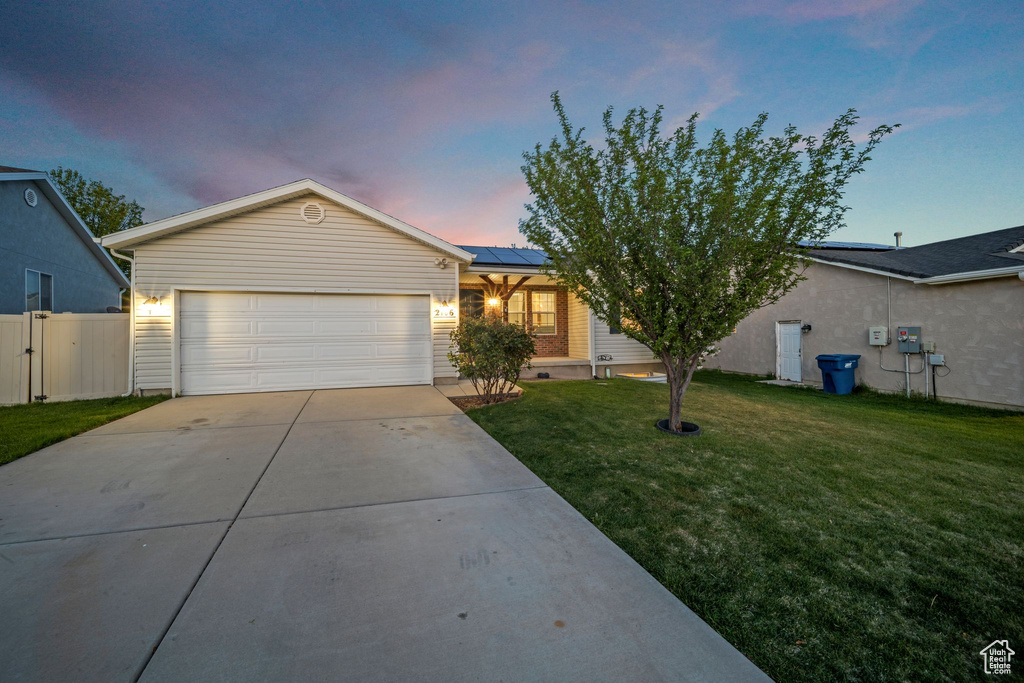 Single story home featuring fence, a garage, a front yard, concrete driveway, and solar panels