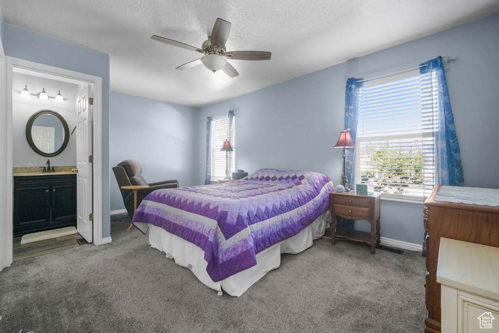 Bedroom featuring ceiling fan, a sink, baseboards, carpet, and ensuite bath