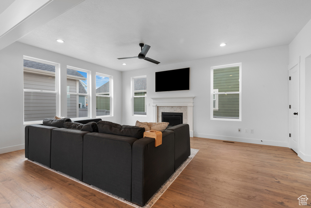 Living area featuring ceiling fan, a fireplace, light wood-style flooring, recessed lighting, and baseboards