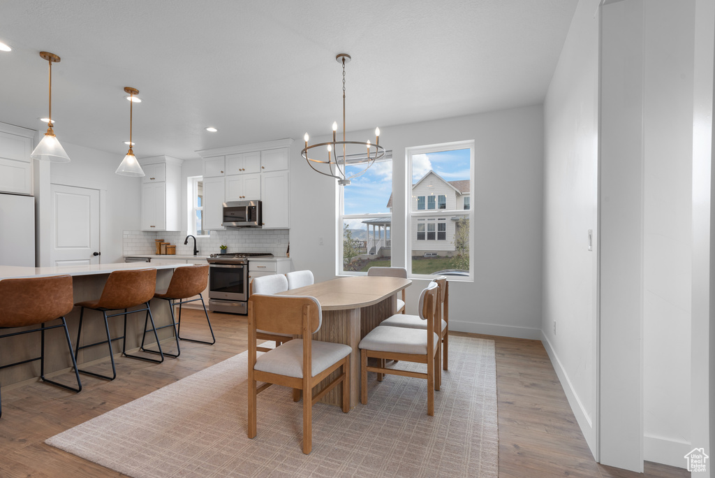 Dining space featuring light wood-style floors, baseboards, recessed lighting, and a notable chandelier