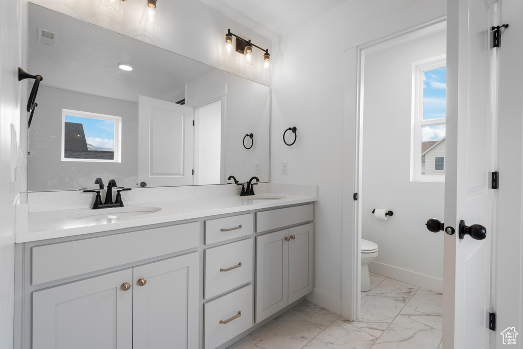 Bathroom featuring a sink, marble finish floor, a wealth of natural light, and toilet