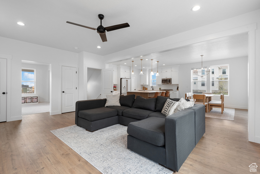 Living room featuring baseboards, a ceiling fan, light wood finished floors, and recessed lighting
