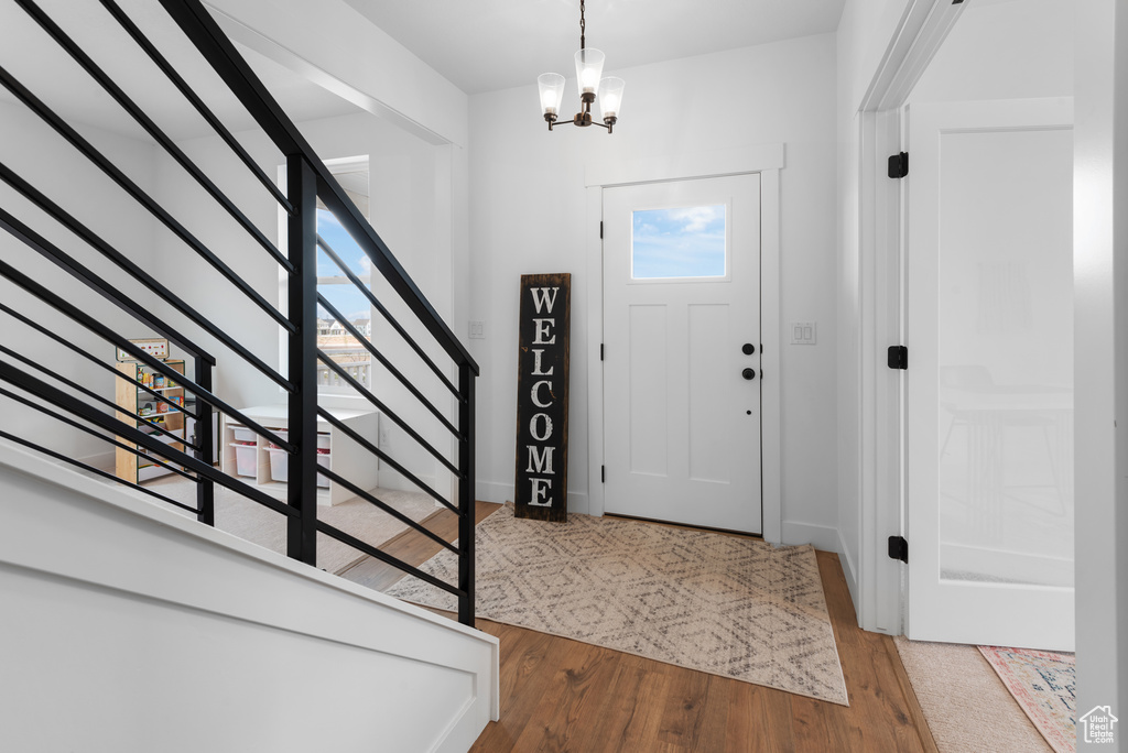 Foyer entrance with stairs, baseboards, an inviting chandelier, and wood finished floors