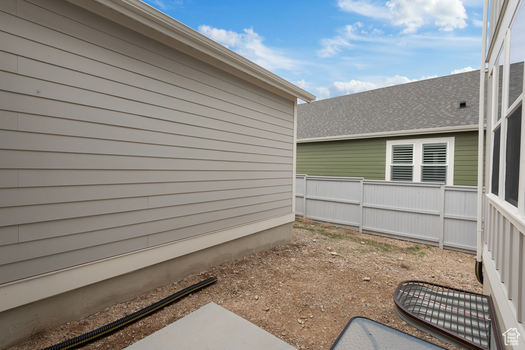 View of side of home with fence and a shingled roof