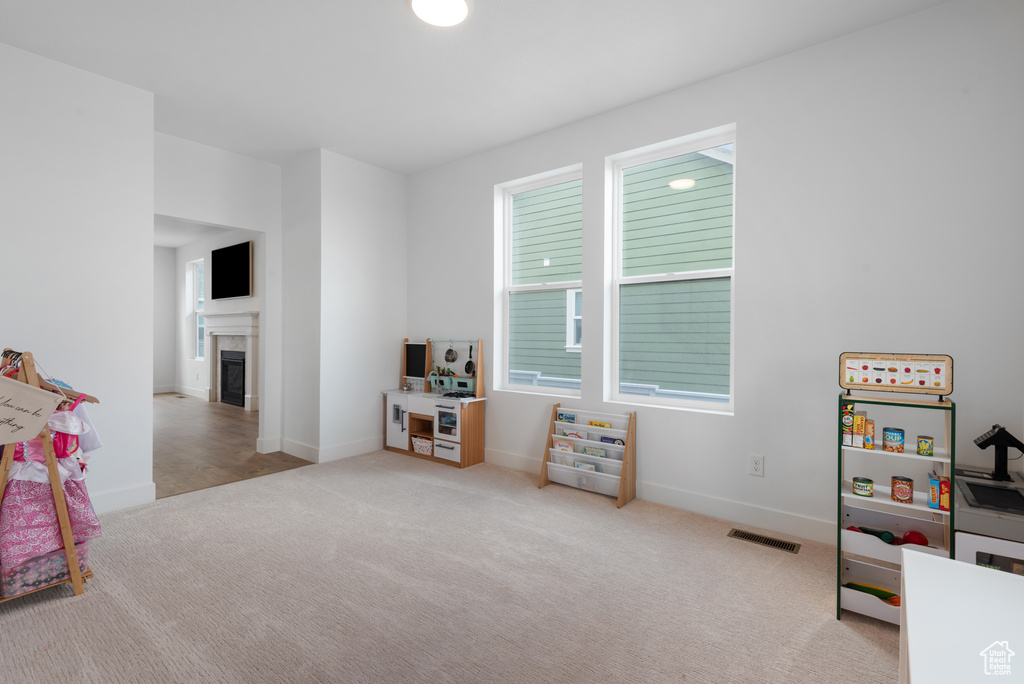 Rec room featuring carpet floors, baseboards, visible vents, and a tile fireplace