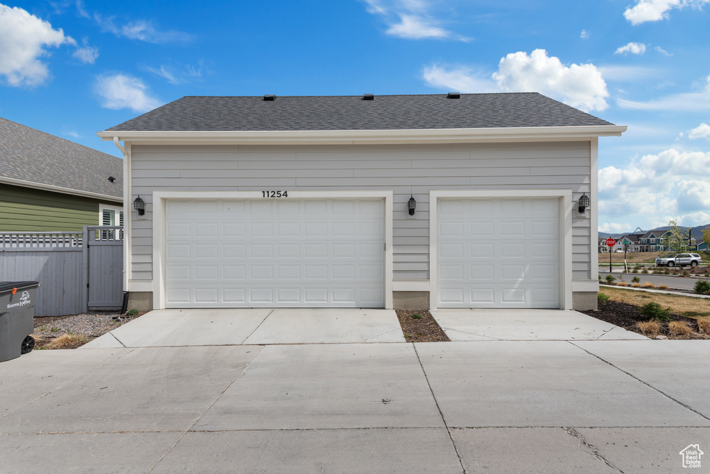 Garage featuring fence and concrete driveway