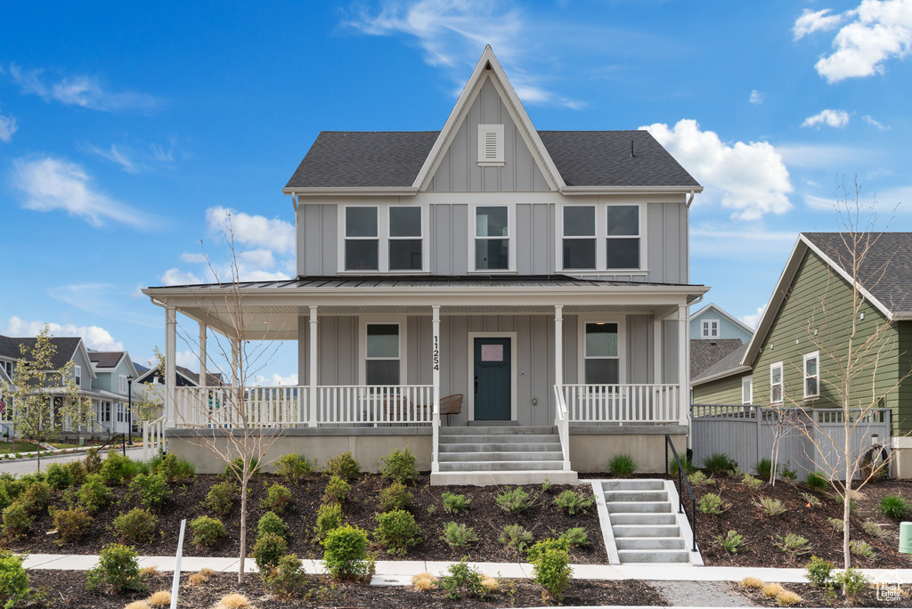 Farmhouse inspired home with board and batten siding, roof with shingles, stairs, and a porch