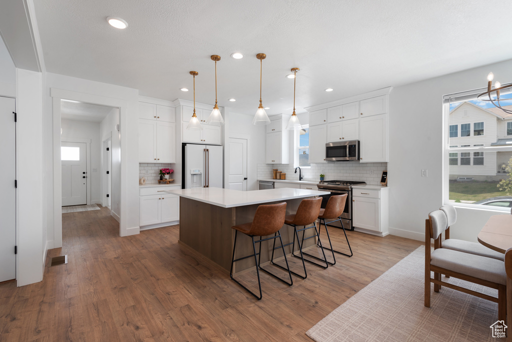 Kitchen featuring white cabinetry, appliances with stainless steel finishes, a kitchen island, and tasteful backsplash