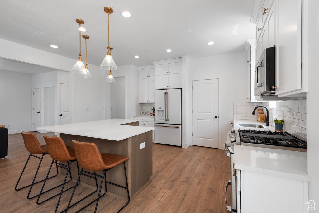 Kitchen with a sink, stainless steel appliances, white cabinetry, tasteful backsplash, and a kitchen island