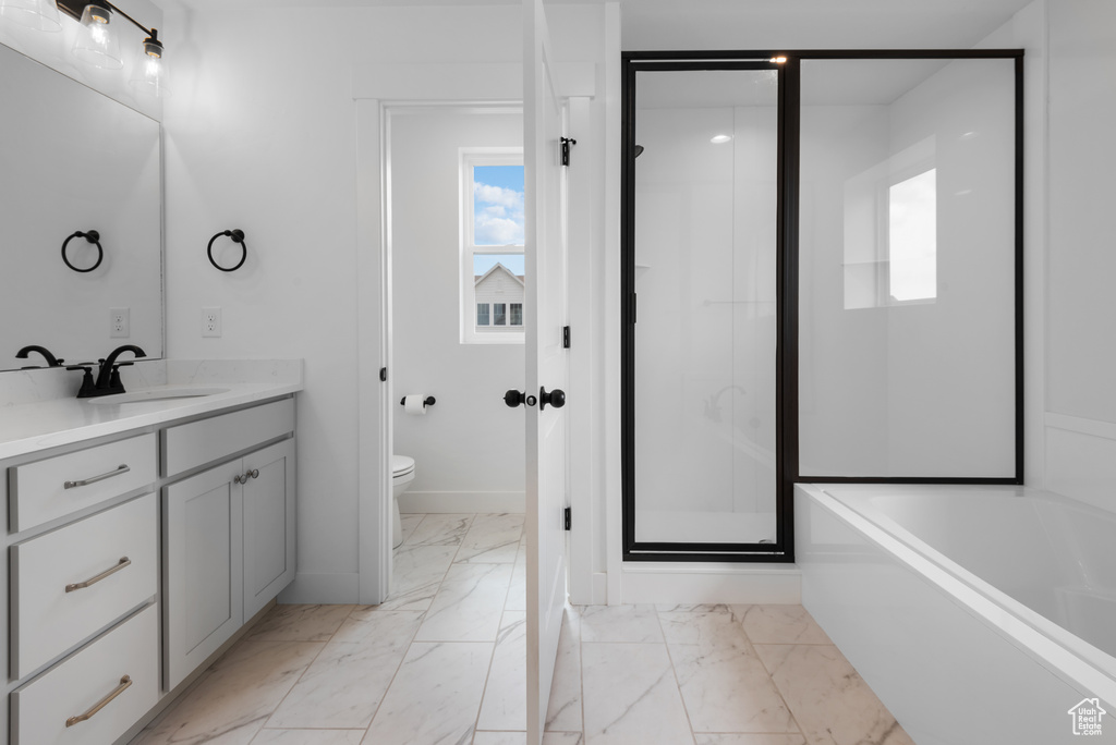 Bathroom featuring toilet, a stall shower, marble finish floor, and vanity