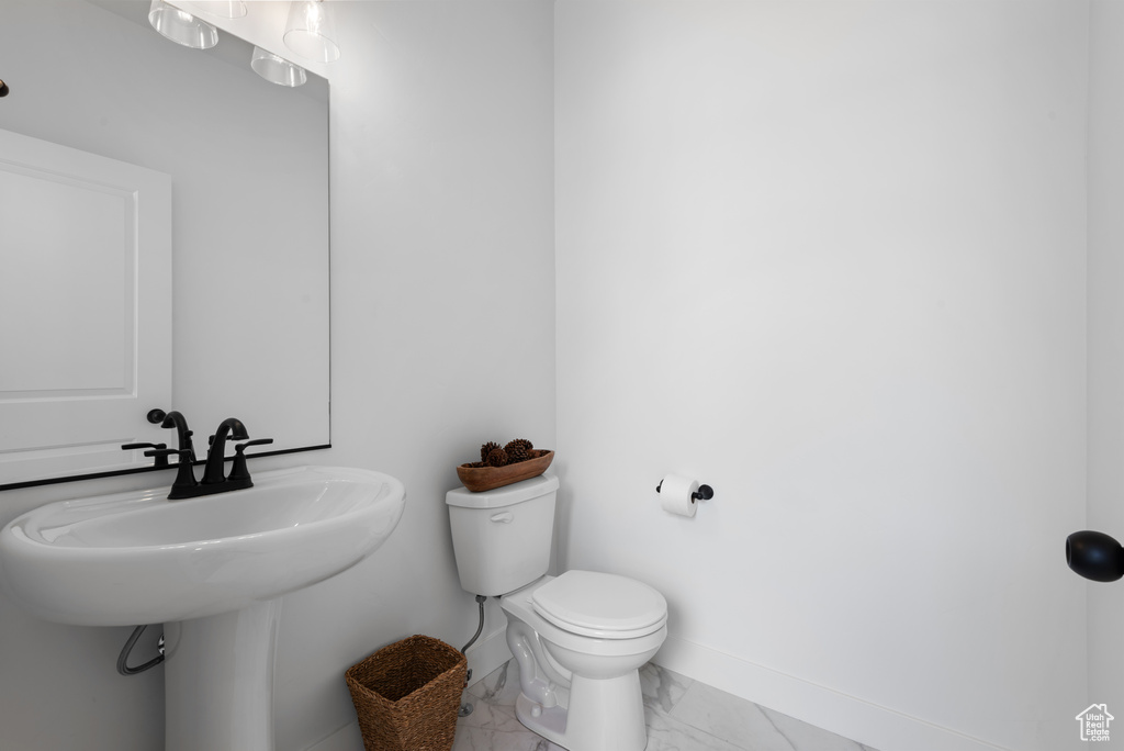 Half bath with baseboards, toilet, and marble finish floor