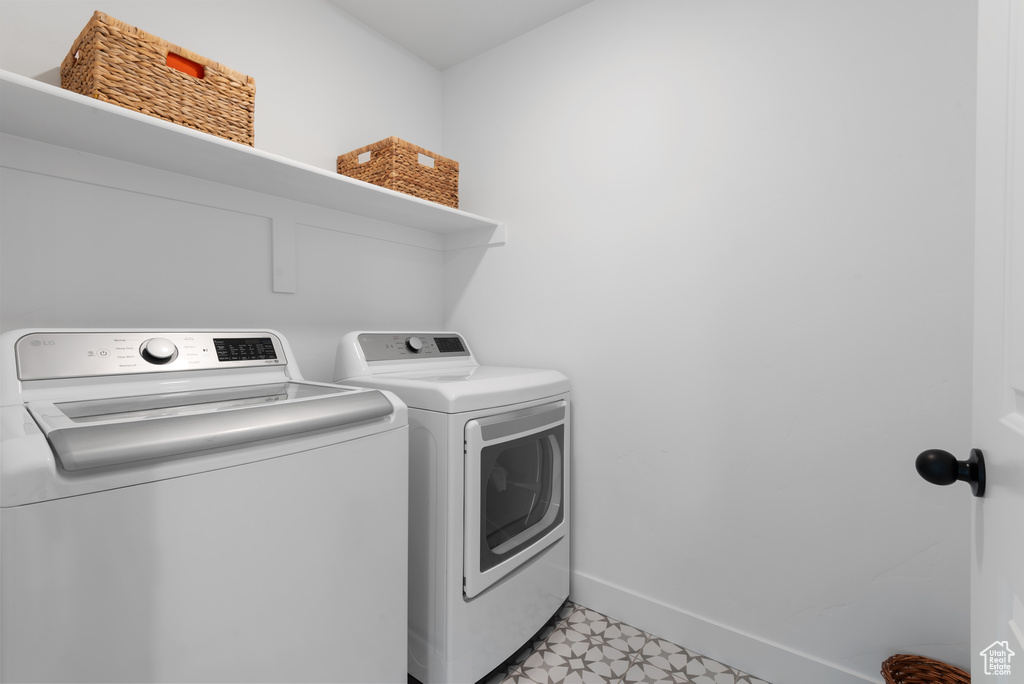 Clothes washing area featuring separate washer and dryer, baseboards, laundry area, and light floors