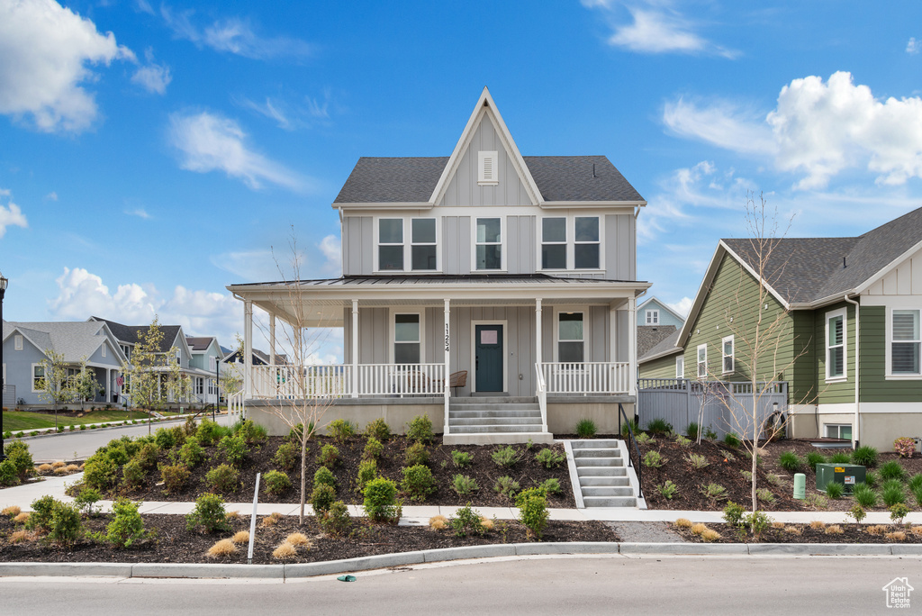 View of front of home with a residential view, board and batten siding, a porch, stairway, and a standing seam roof