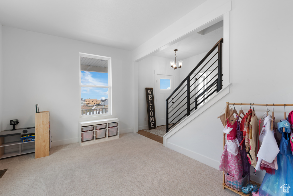 Entrance foyer featuring carpet flooring, baseboards, an inviting chandelier, and stairway