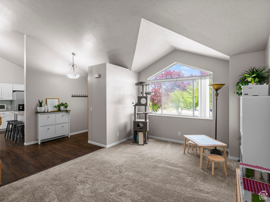 Recreation room featuring baseboards, vaulted ceiling, and dark colored carpet