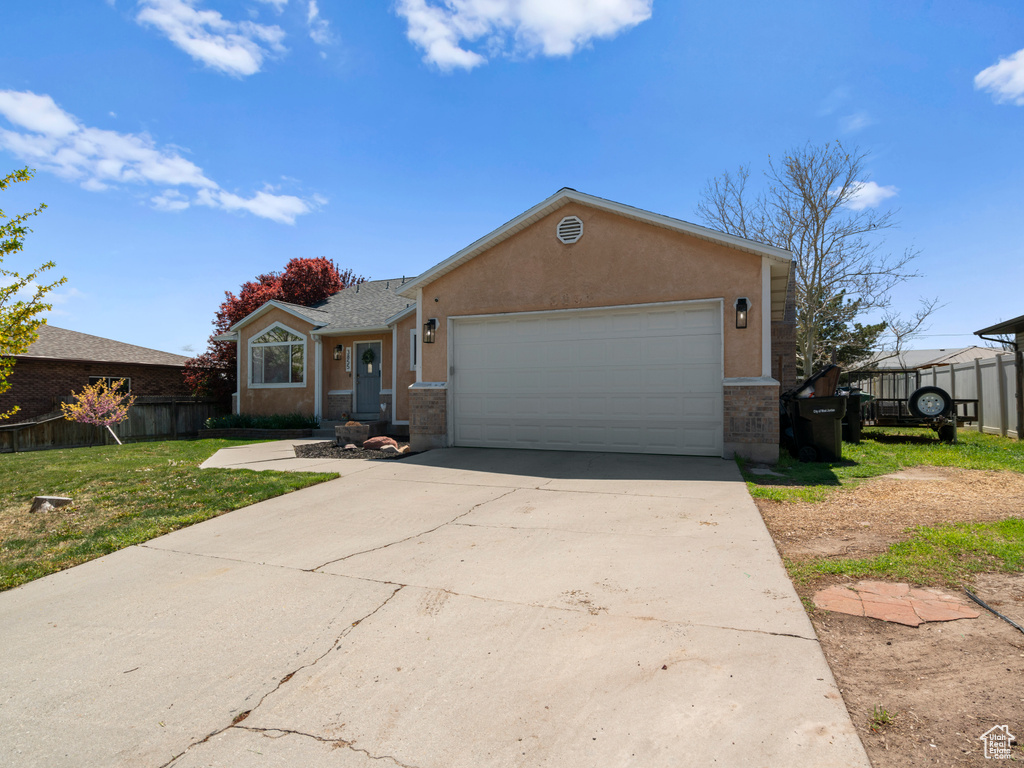 Ranch-style home featuring concrete driveway, stucco siding, fence, and a garage