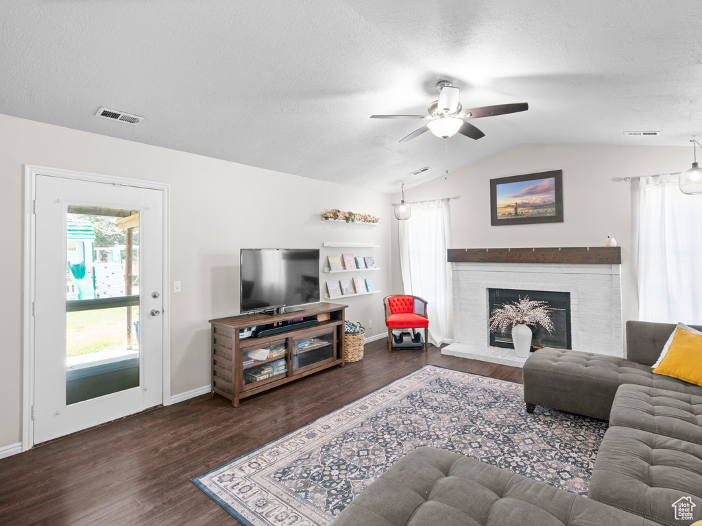 Living room featuring visible vents, a ceiling fan, lofted ceiling, and wood finished floors