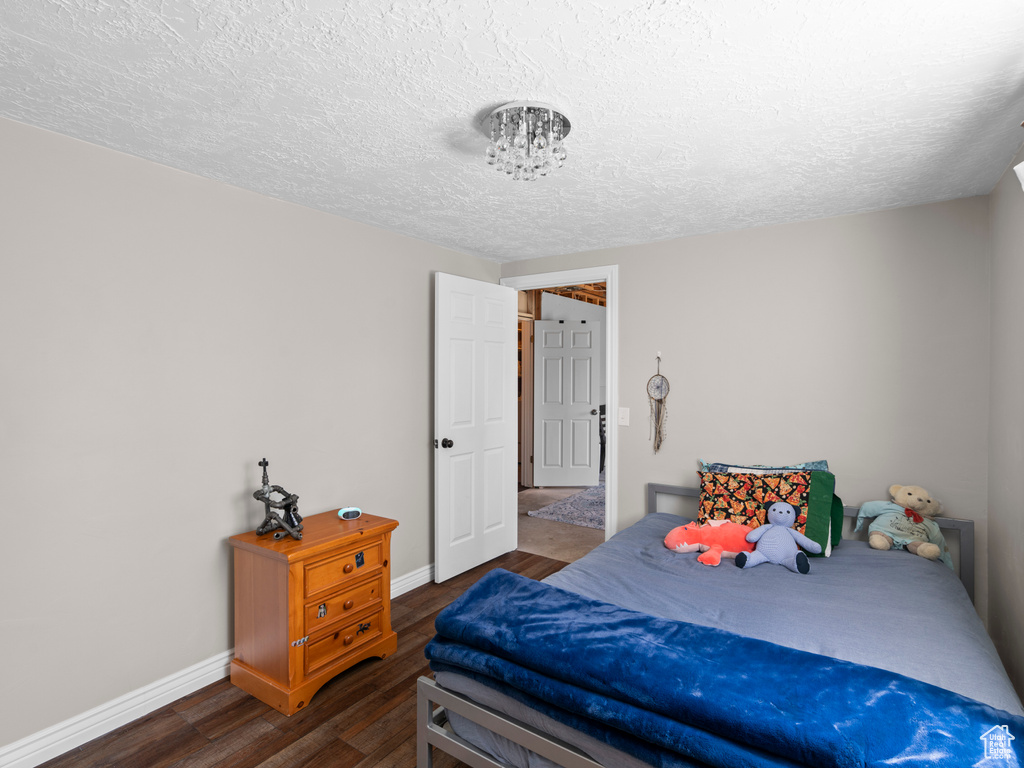 Bedroom featuring baseboards, a textured ceiling, and wood finished floors