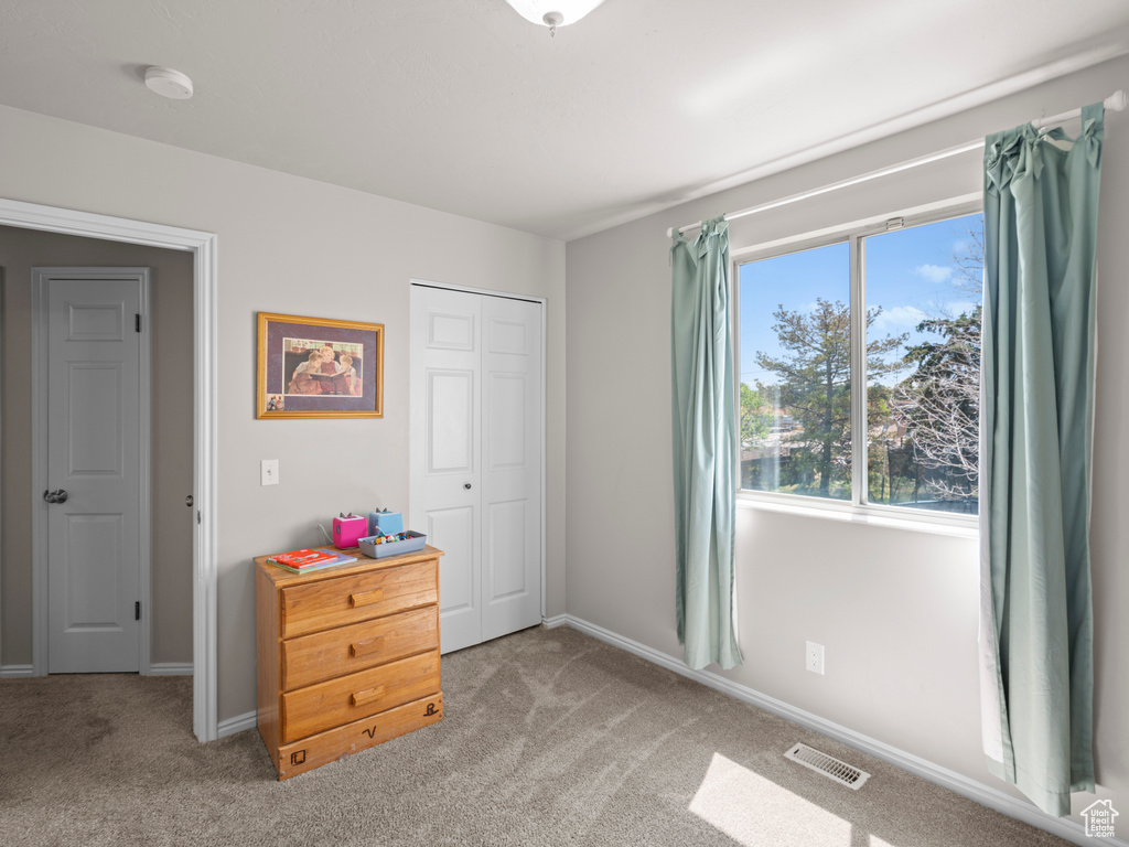 Bedroom with carpet flooring, baseboards, visible vents, and a closet