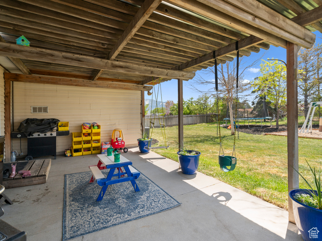 View of patio with fence, a trampoline, a playground, and visible vents