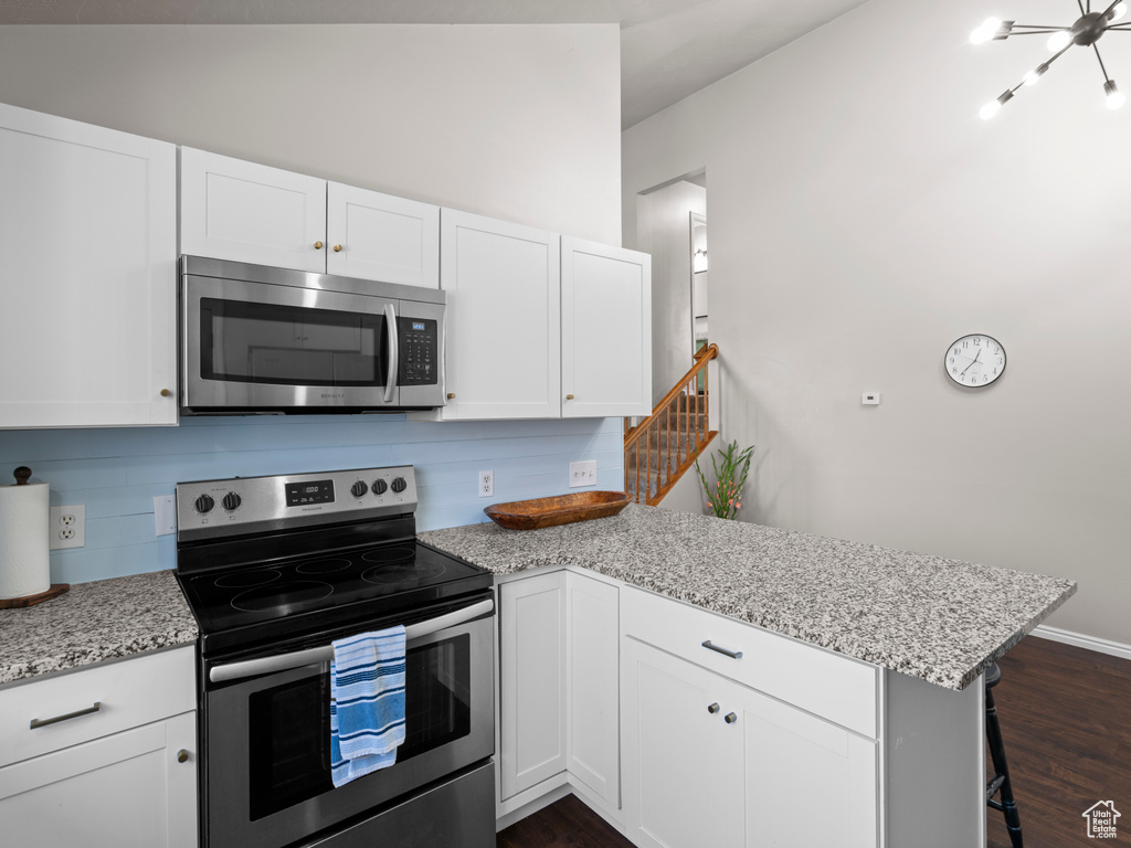 Kitchen with backsplash, a peninsula, white cabinets, and appliances with stainless steel finishes