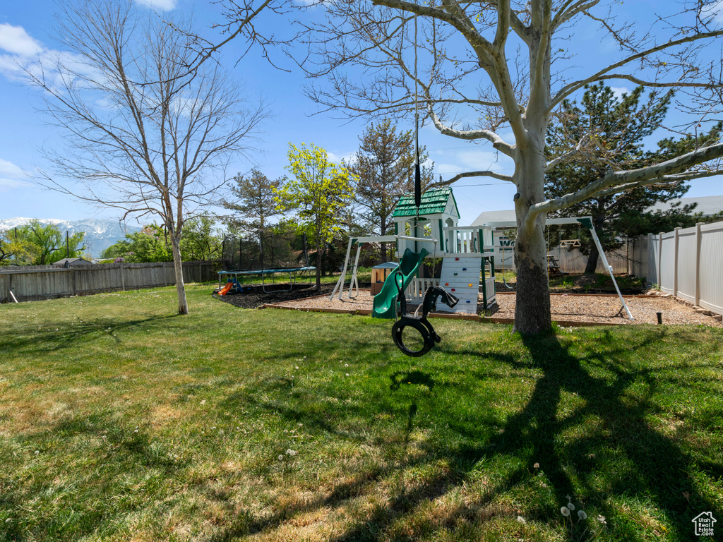 View of yard featuring a playground, a fenced backyard, and a trampoline