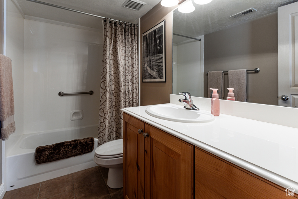 Full bathroom featuring tile patterned flooring, shower / bath combo, toilet, and visible vents