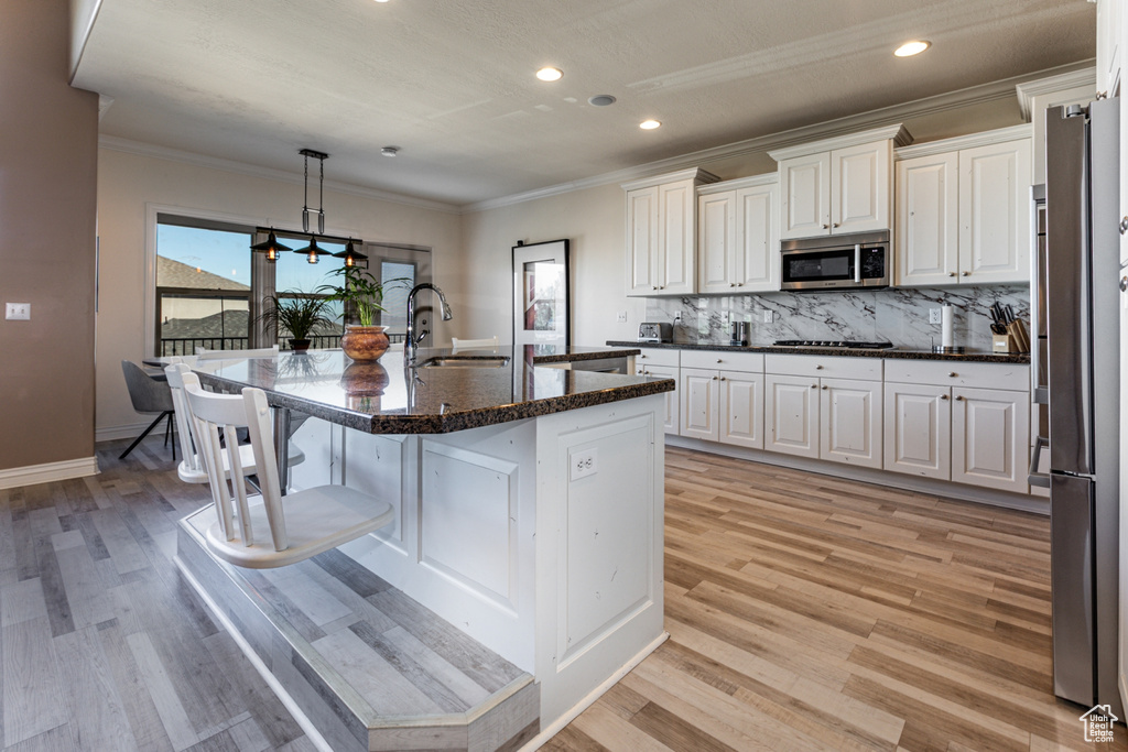 Kitchen featuring a sink, light wood-style floors, crown molding, and stainless steel microwave