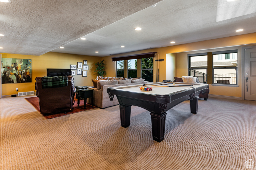 Recreation room featuring recessed lighting, a textured ceiling, light colored carpet, and visible vents