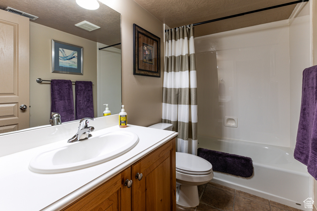Bathroom with toilet, visible vents, shower / bathtub combination with curtain, and vanity