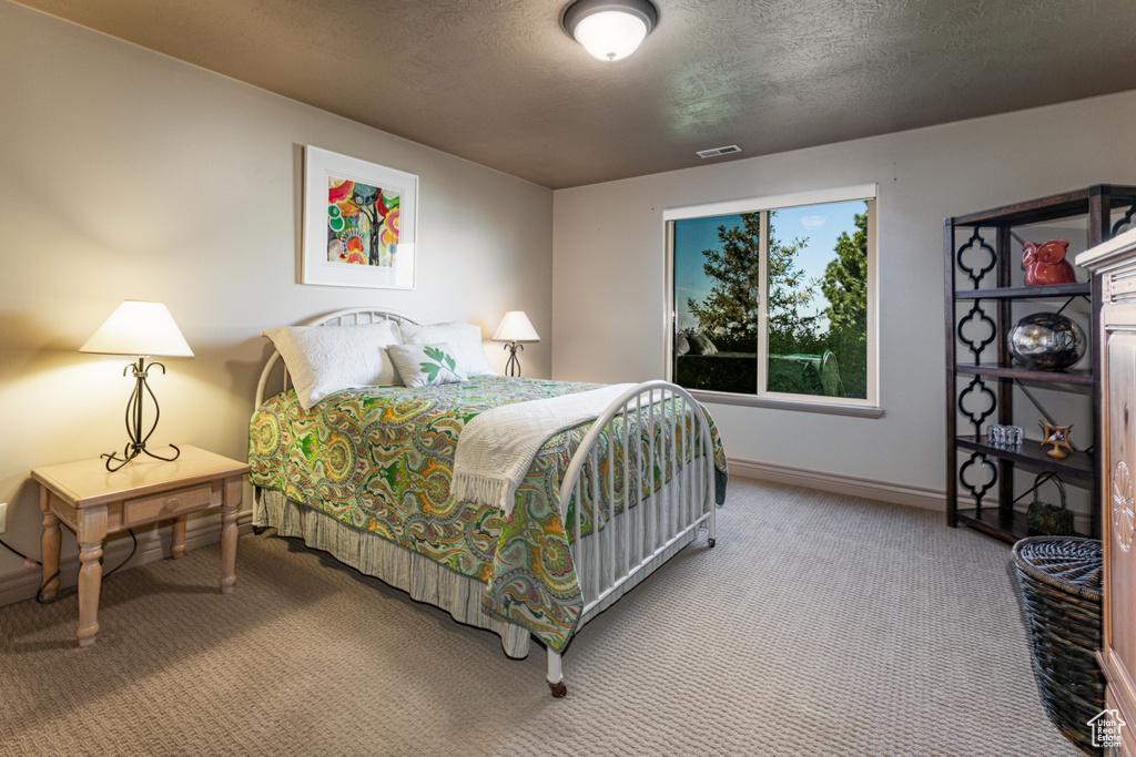 Carpeted bedroom featuring visible vents, a textured ceiling, and baseboards