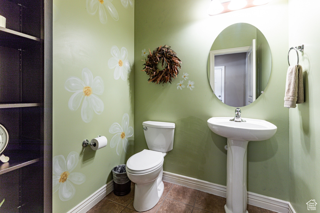 Bathroom featuring tile patterned floors, baseboards, and toilet