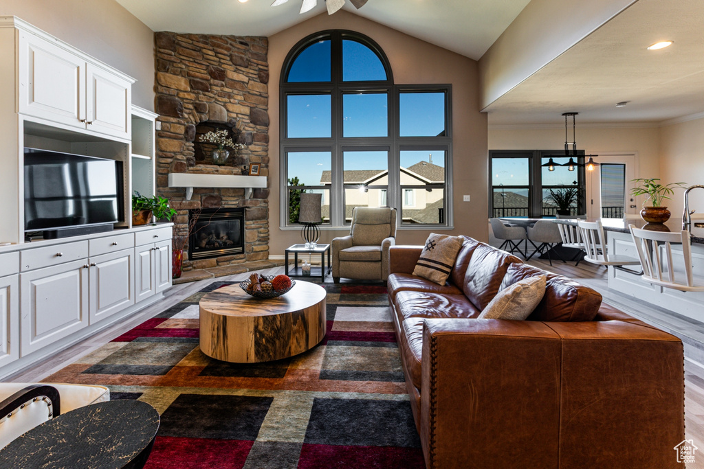 Living area featuring ceiling fan, lofted ceiling, and a fireplace