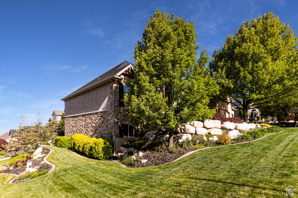 View of property exterior with a yard and stone siding