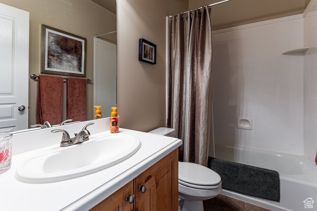 Bathroom featuring a shower with curtain, vanity, and toilet