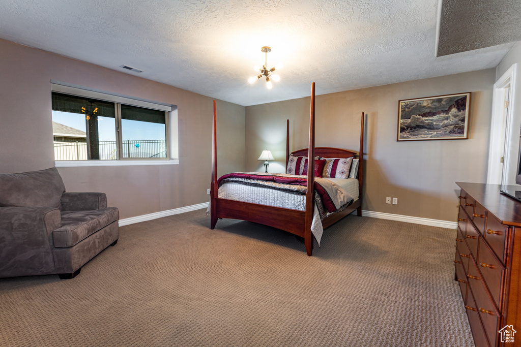 Carpeted bedroom featuring a chandelier, a textured ceiling, visible vents, and baseboards
