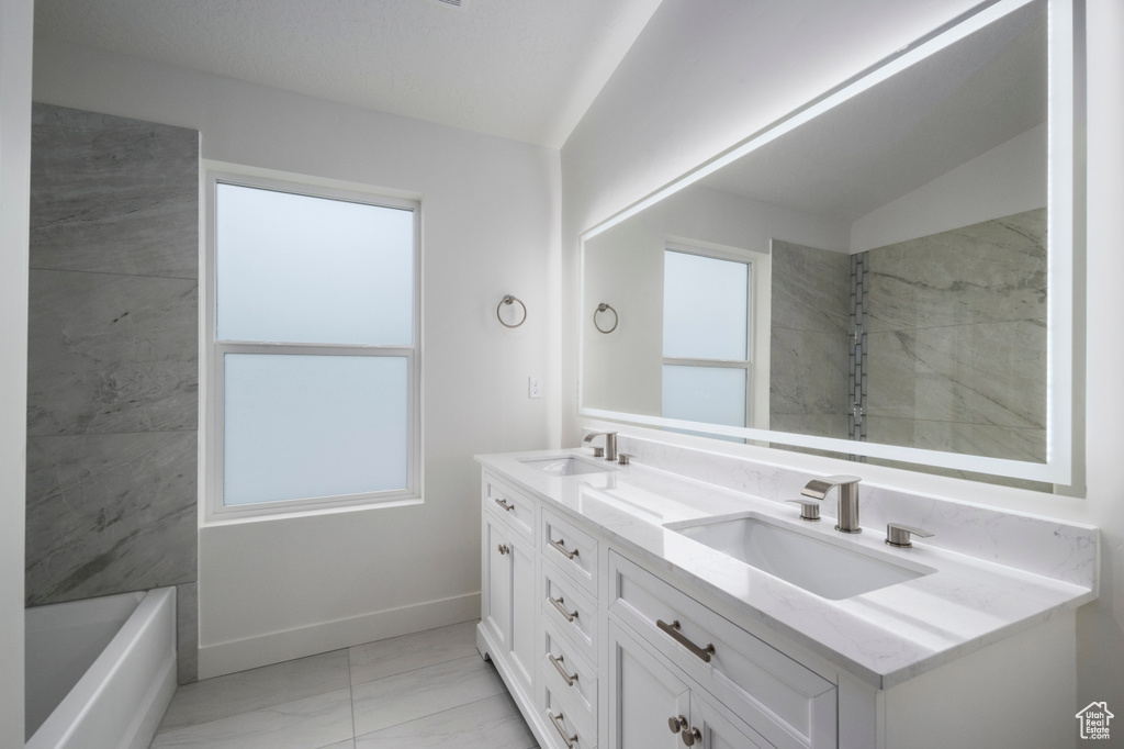 Bathroom with double vanity, a sink, marble finish floor, and baseboards