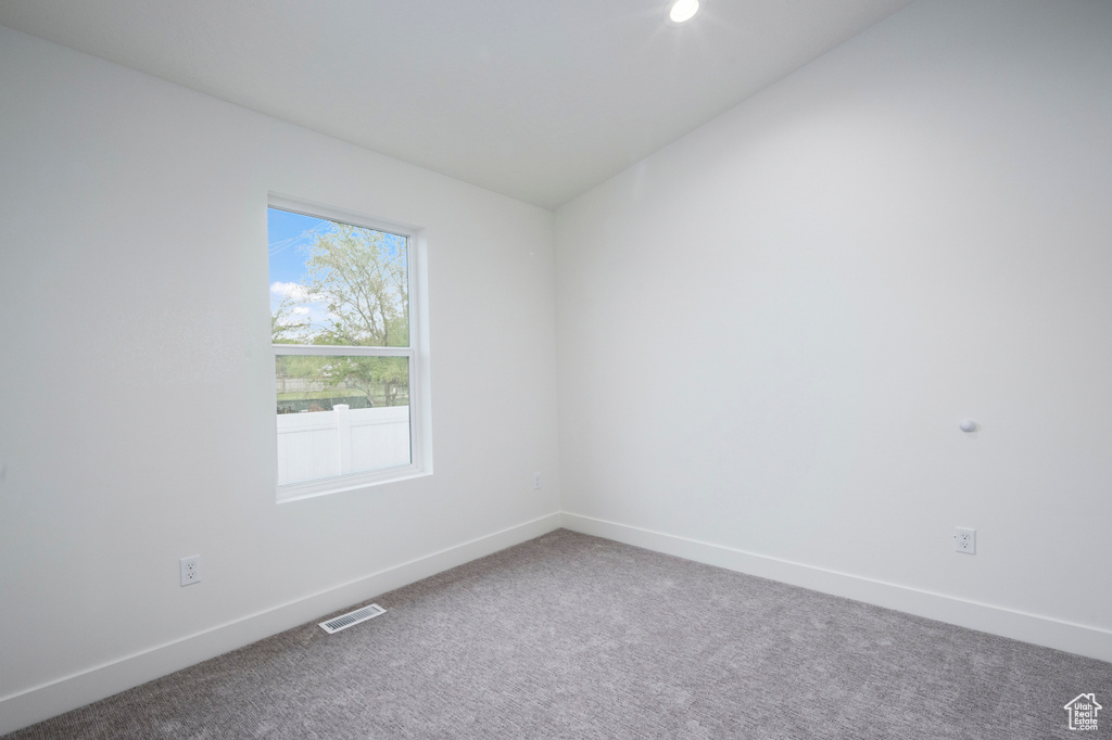 Carpeted spare room with visible vents and baseboards