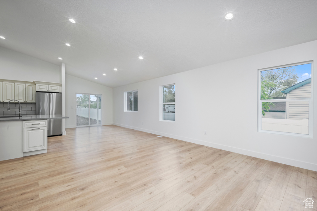 Unfurnished living room featuring recessed lighting, a sink, light wood finished floors, and a wealth of natural light