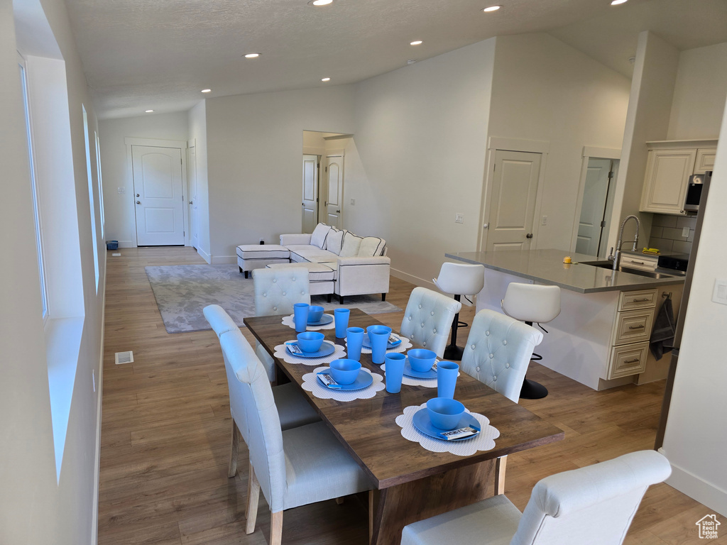Dining area with lofted ceiling, light wood-style flooring, baseboards, and recessed lighting