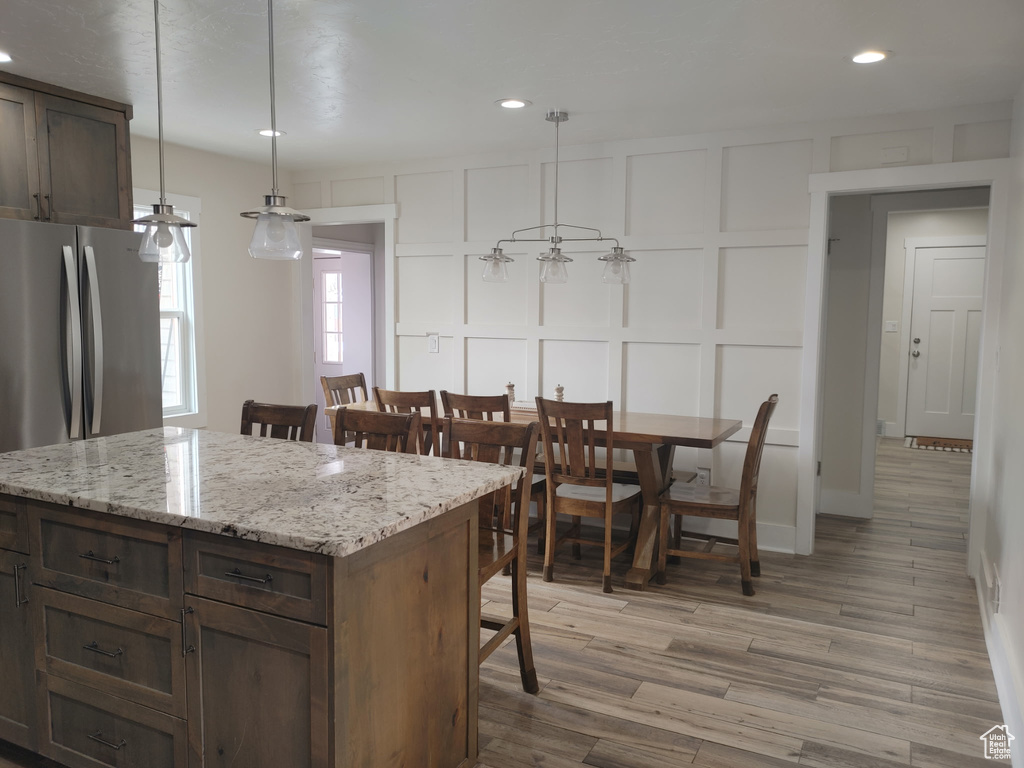 Kitchen with a decorative wall, light wood-style flooring, a center island, recessed lighting, and pendant lighting