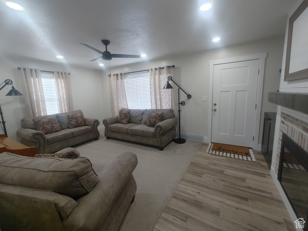 Living room featuring a glass covered fireplace, a ceiling fan, baseboards, recessed lighting, and light wood-type flooring
