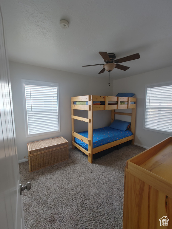 Carpeted bedroom with a ceiling fan and baseboards