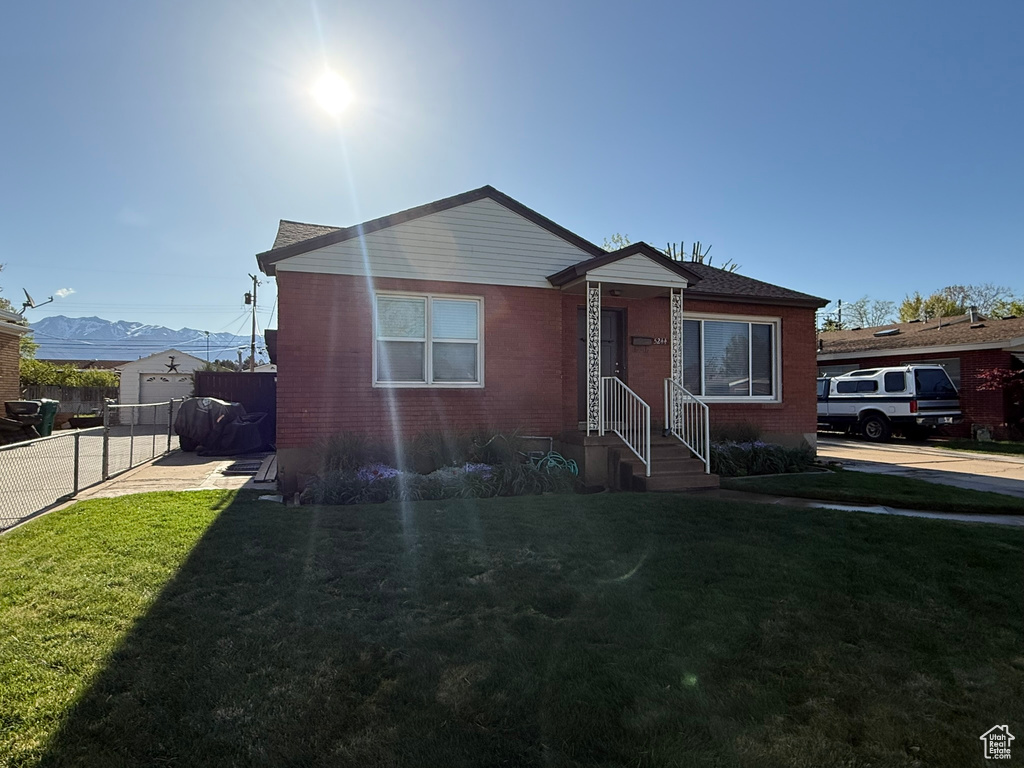 Bungalow-style home featuring fence, concrete driveway, a front lawn, and brick siding