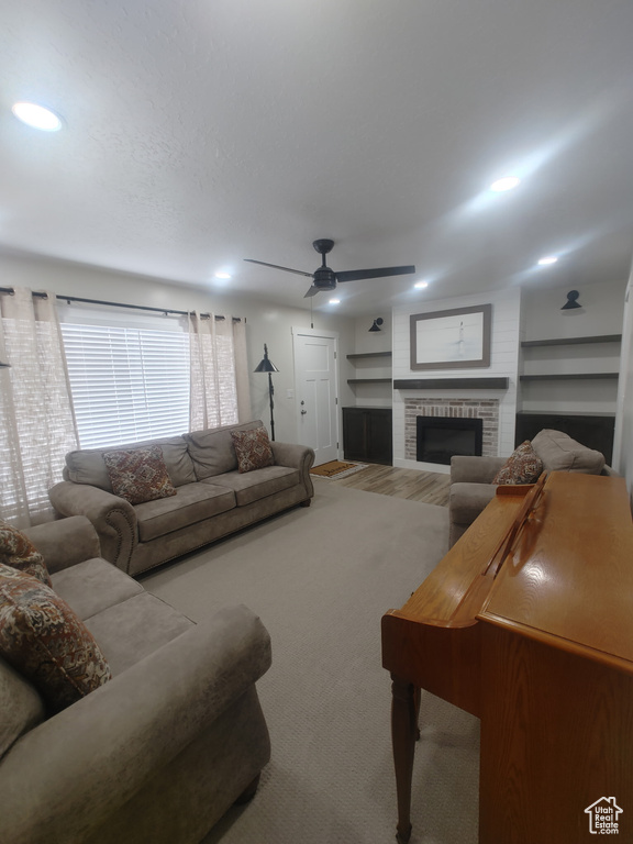 Living room with a fireplace, a ceiling fan, and wood finished floors