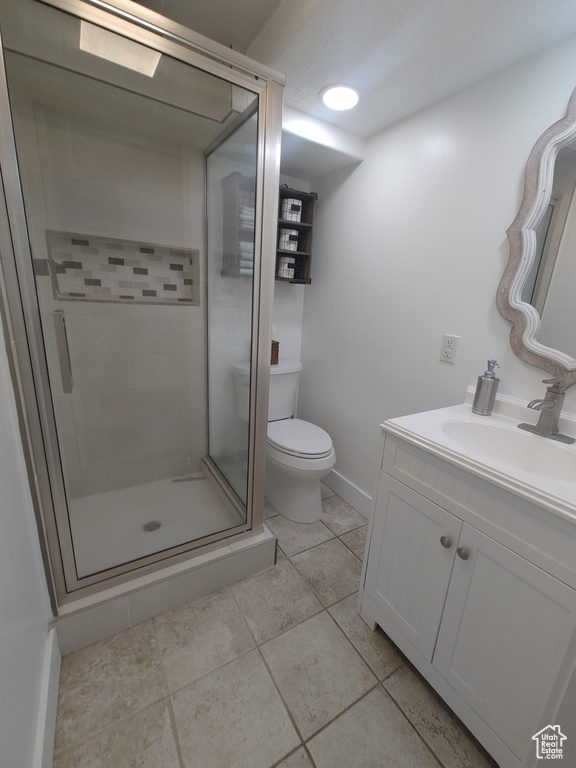 Bathroom with vanity, toilet, tile patterned floors, baseboards, and a shower stall