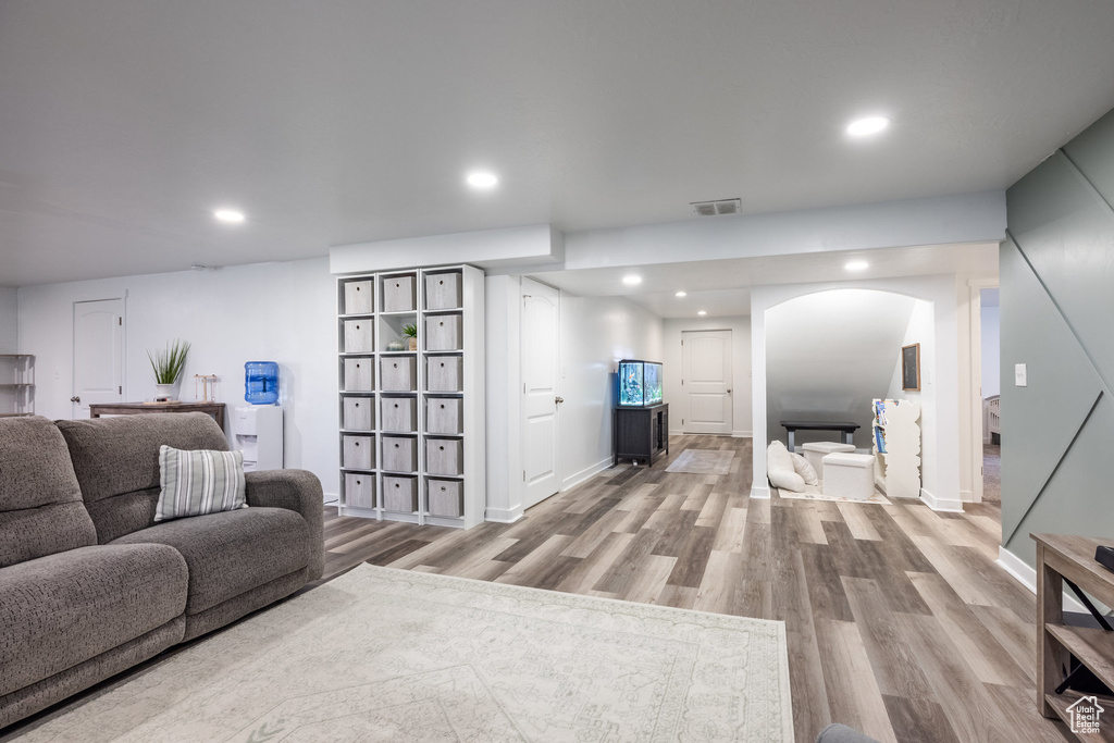 Living area with visible vents, arched walkways, wood finished floors, and recessed lighting