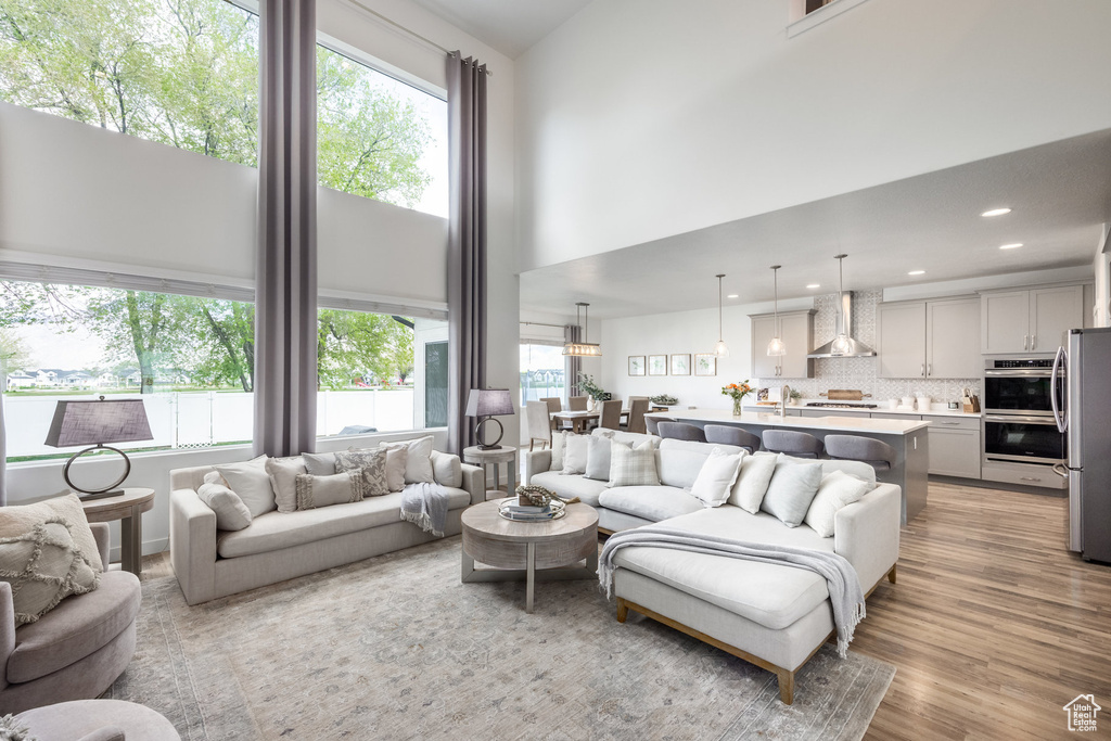 Living area with recessed lighting, light wood-type flooring, and a towering ceiling