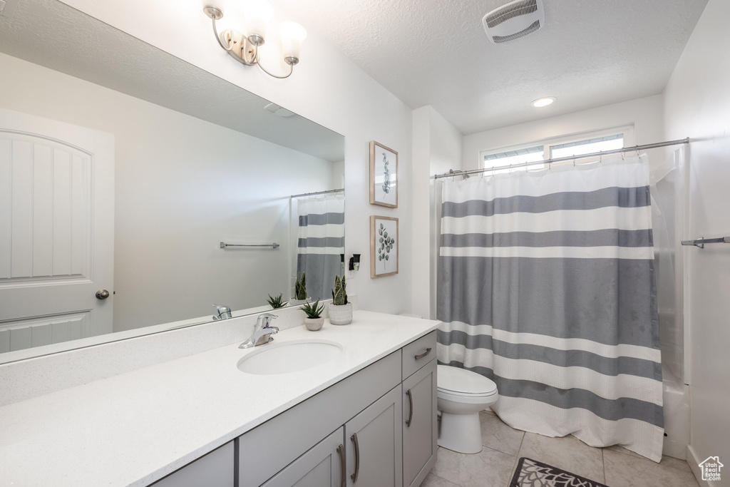 Bathroom with toilet, tile patterned floors, a shower with shower curtain, and vanity