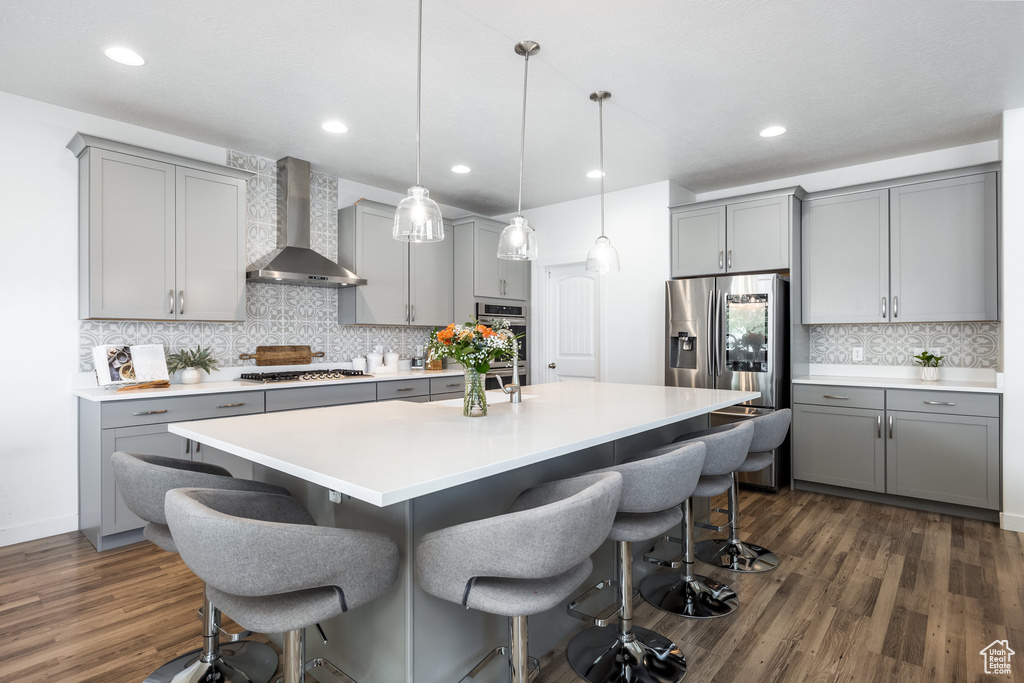 Kitchen with gray cabinetry and wall chimney exhaust hood